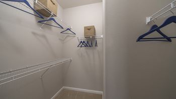 A walk in closet with two hanging racks and a box on the wall